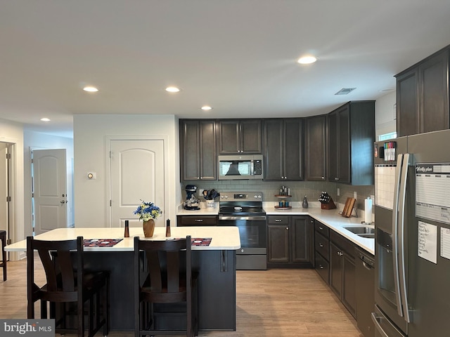 kitchen featuring stainless steel appliances, a center island, a kitchen breakfast bar, and light wood-type flooring