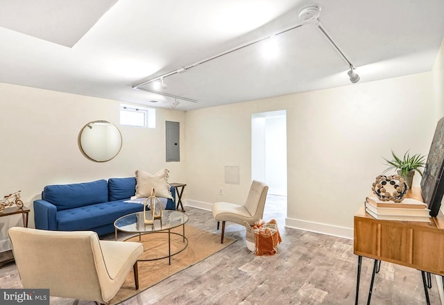 living area with baseboards, electric panel, track lighting, and wood finished floors