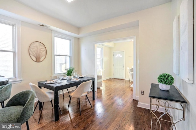 dining space featuring a wealth of natural light, baseboards, visible vents, and dark wood-style flooring