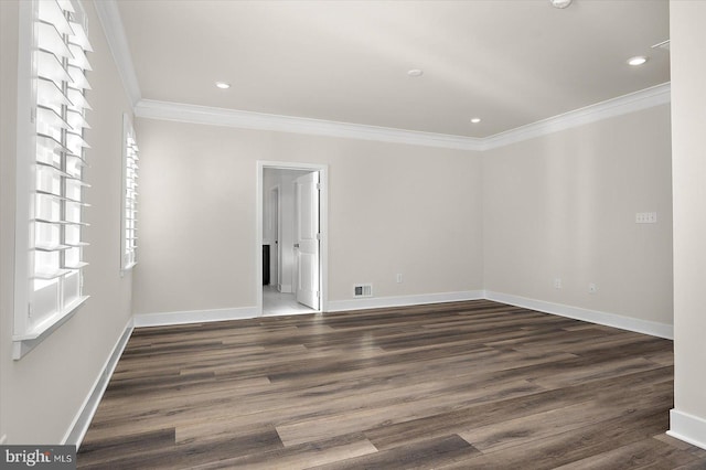 empty room featuring dark wood-style floors, crown molding, baseboards, and visible vents