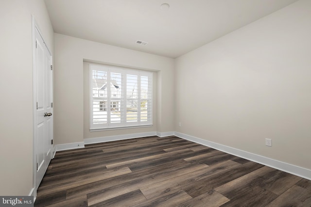 spare room with baseboards, visible vents, and dark wood-style flooring