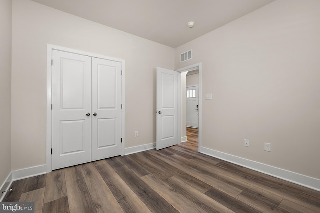unfurnished bedroom featuring baseboards, visible vents, a closet, and dark wood finished floors