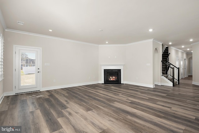 unfurnished living room featuring stairs, recessed lighting, a fireplace with flush hearth, arched walkways, and dark wood-style floors
