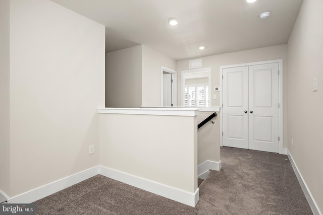 hallway with an upstairs landing, baseboards, dark colored carpet, and recessed lighting