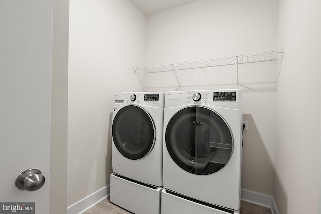 clothes washing area featuring baseboards, washer and dryer, and laundry area