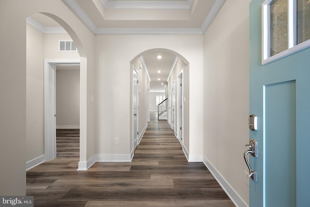 corridor featuring ornamental molding, baseboards, dark wood finished floors, arched walkways, and visible vents