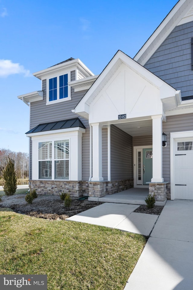view of front of property with a standing seam roof, metal roof, a front yard, and stone siding