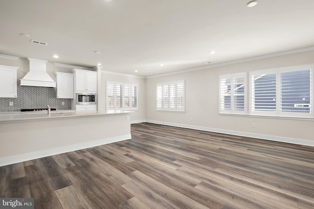 unfurnished living room with dark wood-style floors, visible vents, and crown molding