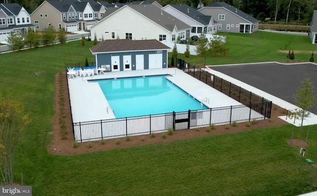 community pool featuring a patio, fence, a yard, and a residential view