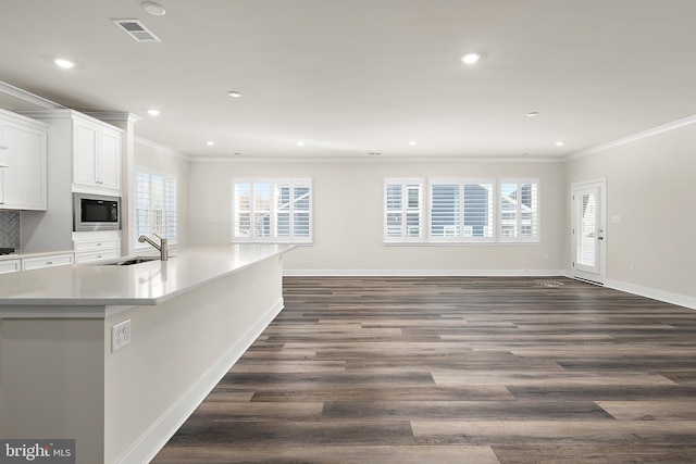 kitchen with white cabinets, visible vents, a sink, open floor plan, and built in microwave