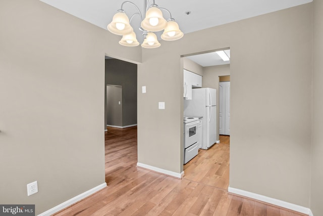 kitchen with white electric stove, light wood-style floors, white cabinets, hanging light fixtures, and light countertops