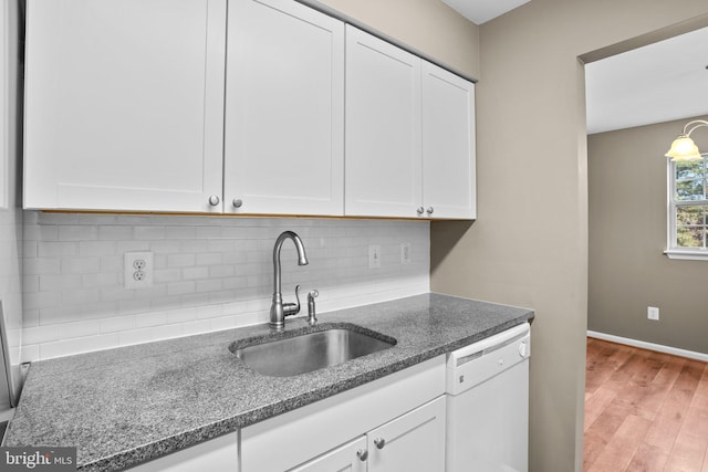 kitchen featuring tasteful backsplash, white dishwasher, a sink, and white cabinetry