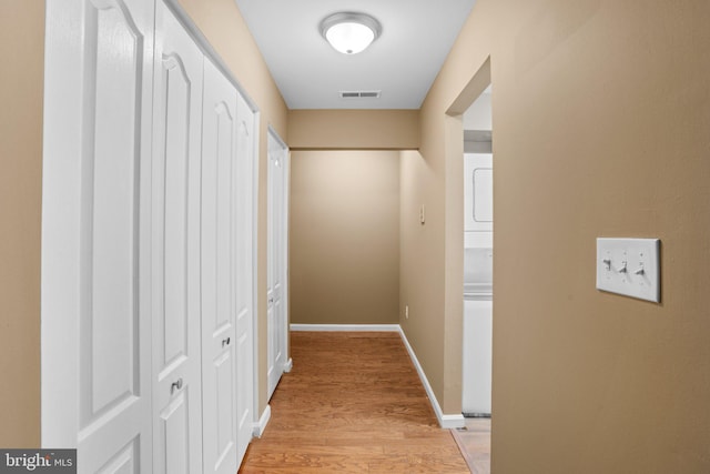 corridor featuring light wood-style floors, baseboards, and visible vents