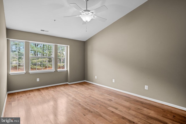 unfurnished room with visible vents, light wood-style flooring, a ceiling fan, vaulted ceiling, and baseboards