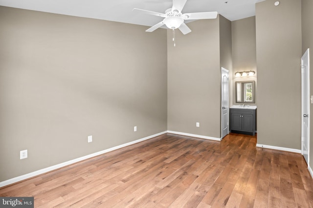 unfurnished bedroom featuring a sink, ensuite bath, baseboards, and dark wood-style flooring