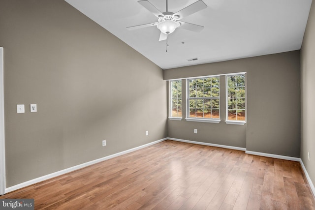 spare room featuring visible vents, vaulted ceiling, ceiling fan, light wood-type flooring, and baseboards