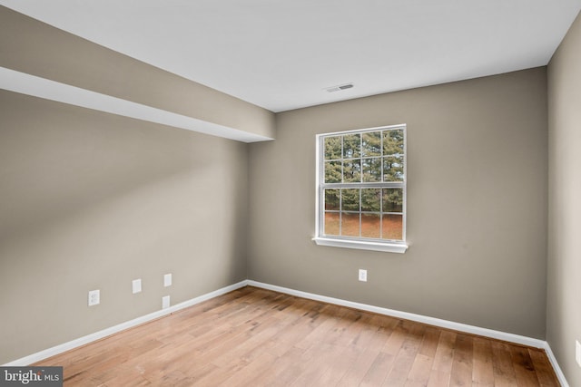 spare room with light wood-style flooring, visible vents, and baseboards