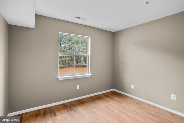 spare room featuring light wood-type flooring, baseboards, and visible vents