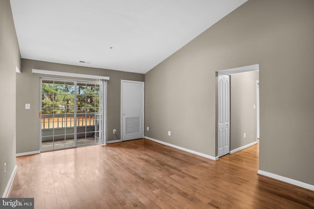 unfurnished room with lofted ceiling, visible vents, baseboards, and wood finished floors