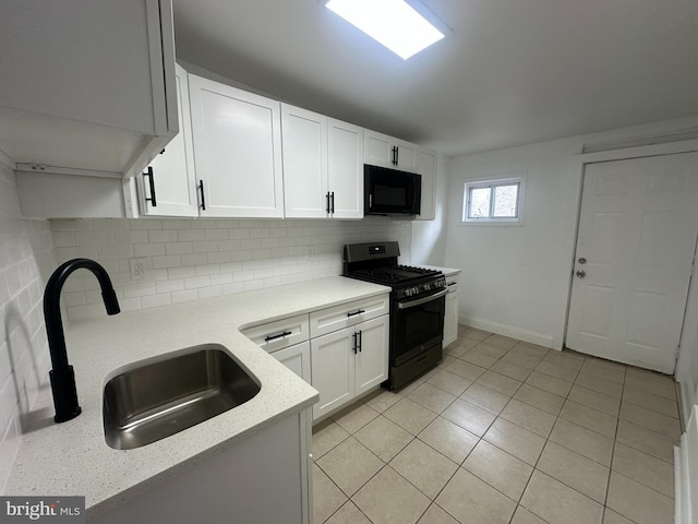 kitchen featuring sink, backsplash, white cabinets, light stone counters, and black appliances