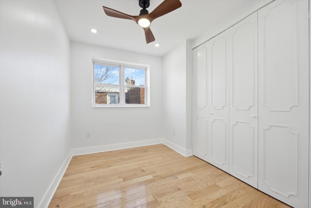 unfurnished bedroom with ceiling fan, light wood-type flooring, and a closet