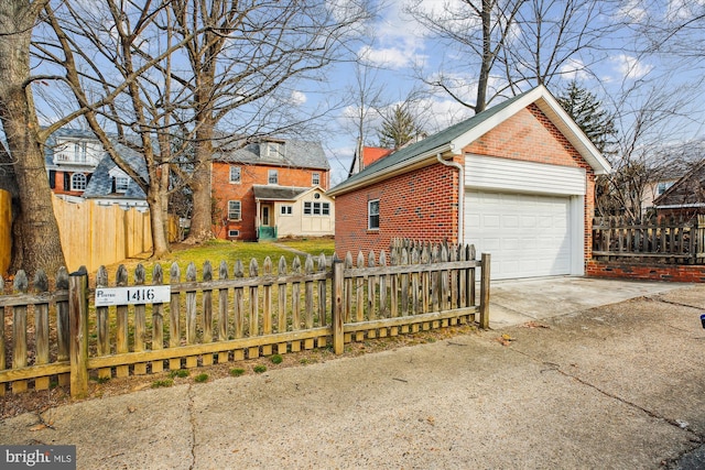 view of home's exterior featuring an outbuilding, brick siding, a fenced front yard, and a detached garage