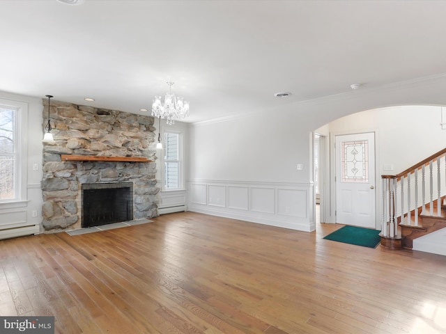 unfurnished living room with light wood finished floors, a baseboard heating unit, stairway, ornamental molding, and a fireplace