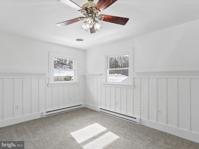 carpeted empty room featuring baseboard heating, plenty of natural light, and visible vents