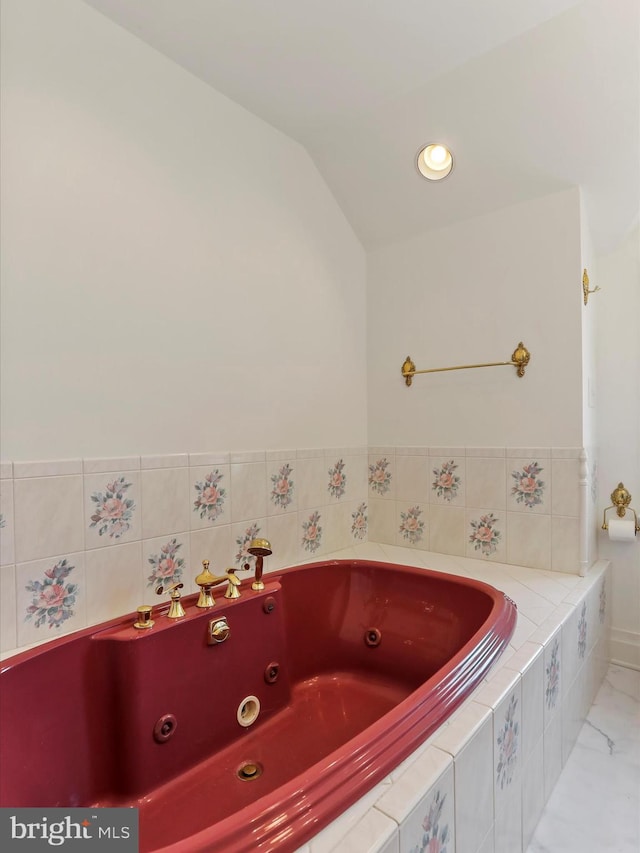 bathroom featuring lofted ceiling and a tub with jets