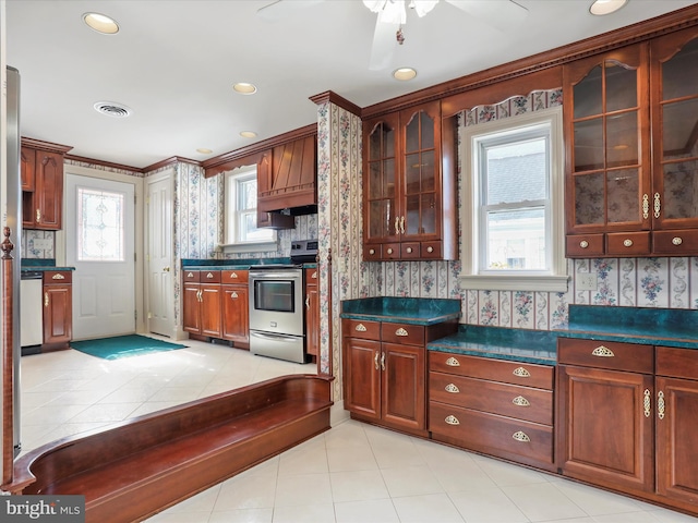 kitchen with dark countertops, visible vents, stainless steel range with electric cooktop, and glass insert cabinets