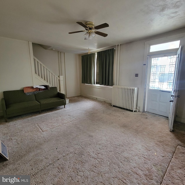 unfurnished living room with radiator, ceiling fan, and carpet