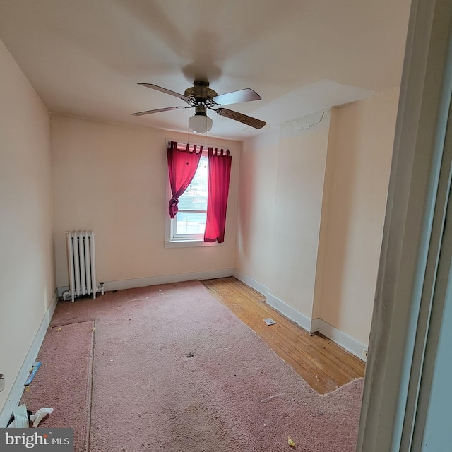 spare room featuring radiator heating unit, ceiling fan, and light hardwood / wood-style flooring