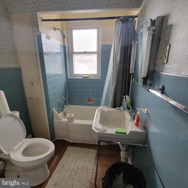 full bathroom featuring hardwood / wood-style flooring, shower / tub combo with curtain, toilet, and sink