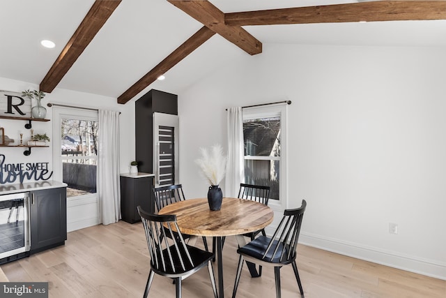 dining area with beverage cooler, lofted ceiling with beams, and light hardwood / wood-style flooring