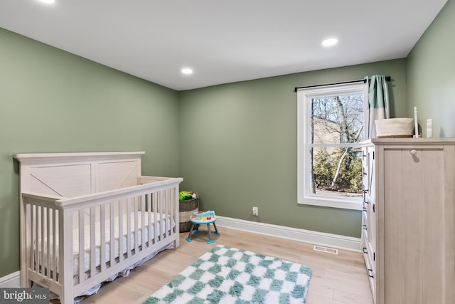 bedroom with a crib and light hardwood / wood-style flooring