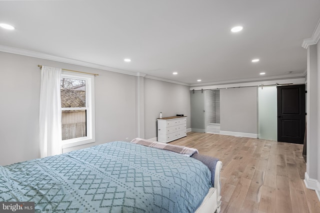 bedroom featuring crown molding, a barn door, and light wood-type flooring