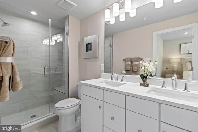 bathroom featuring vanity, a shower with shower door, and toilet