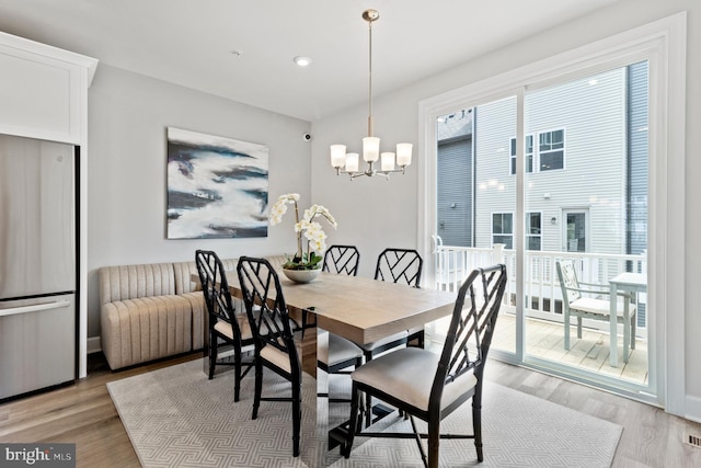 dining space featuring light hardwood / wood-style flooring and a notable chandelier