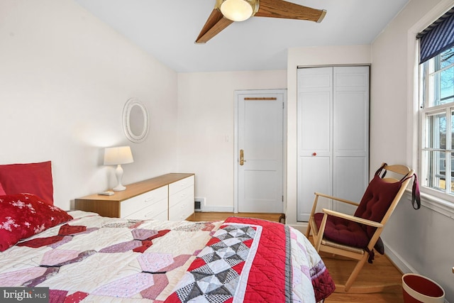 bedroom with light wood finished floors, a closet, visible vents, ceiling fan, and baseboards