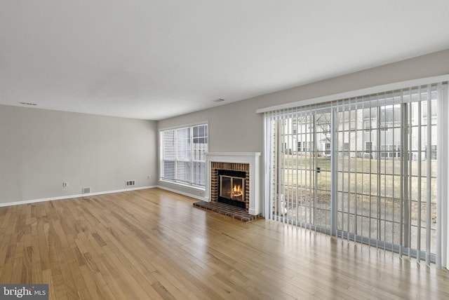 unfurnished living room with visible vents, a fireplace, light wood-style flooring, and baseboards