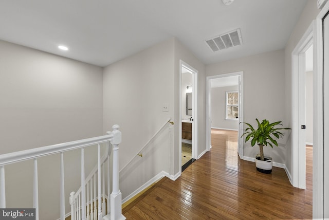 corridor with baseboards, visible vents, dark wood-type flooring, an upstairs landing, and recessed lighting