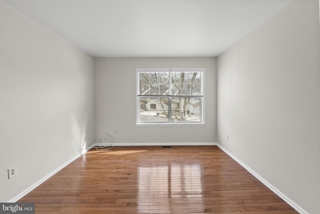 empty room with baseboards and wood finished floors