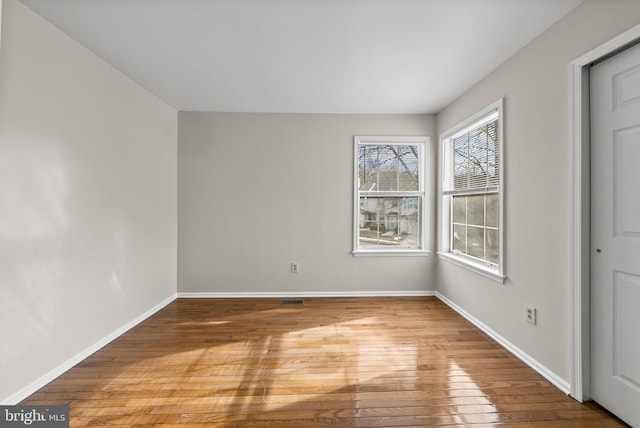 empty room featuring light wood finished floors, visible vents, and baseboards