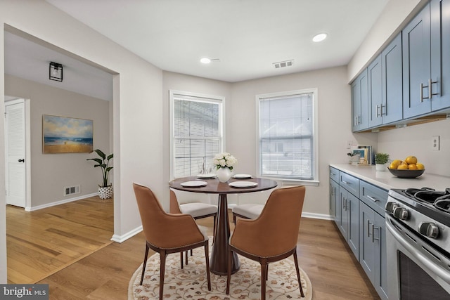 dining space featuring light wood-style floors, visible vents, and baseboards