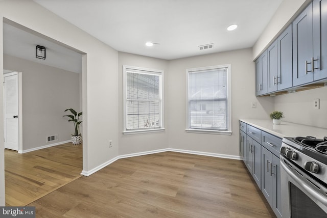 kitchen with stainless steel gas stove, baseboards, light wood-style flooring, gray cabinets, and light countertops