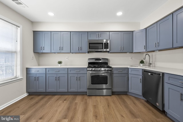 kitchen featuring visible vents, stainless steel appliances, light countertops, a healthy amount of sunlight, and a sink