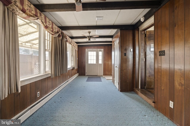 corridor with carpet, wooden walls, a baseboard heating unit, and beam ceiling