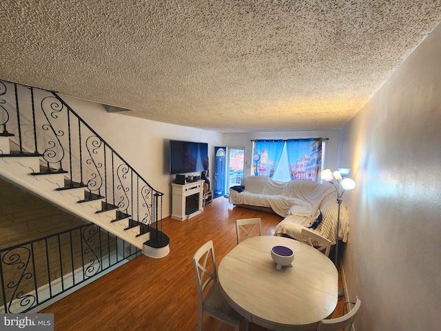 living room featuring stairs, a textured ceiling, and wood finished floors