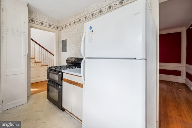 kitchen with white cabinets, double oven range, light countertops, and freestanding refrigerator