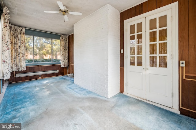 spare room with carpet floors, a baseboard radiator, wood walls, and brick wall